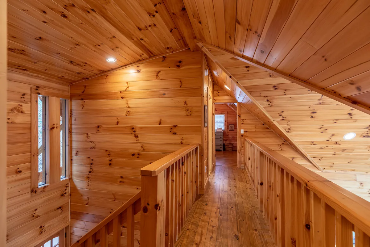 A rustic wooden railing and pine wood walls evoke the feel of a mountain lodge. The image captures a hallway or open area, suggesting movement, exploration, and the spirit of adventure within a warm, inviting setting.